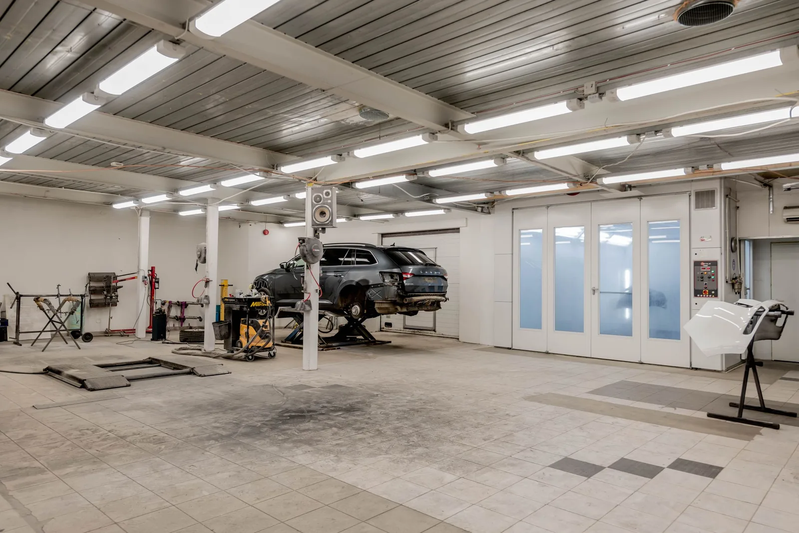 Leere Kfz-Werkstatt mit einem Auto auf der Hebebühne