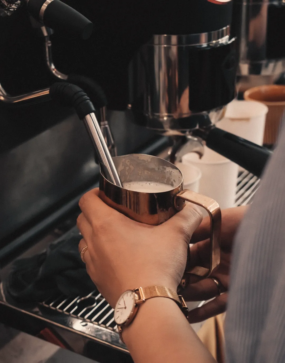 Barista schäumt Milch an der Espressomaschine eines Cafés